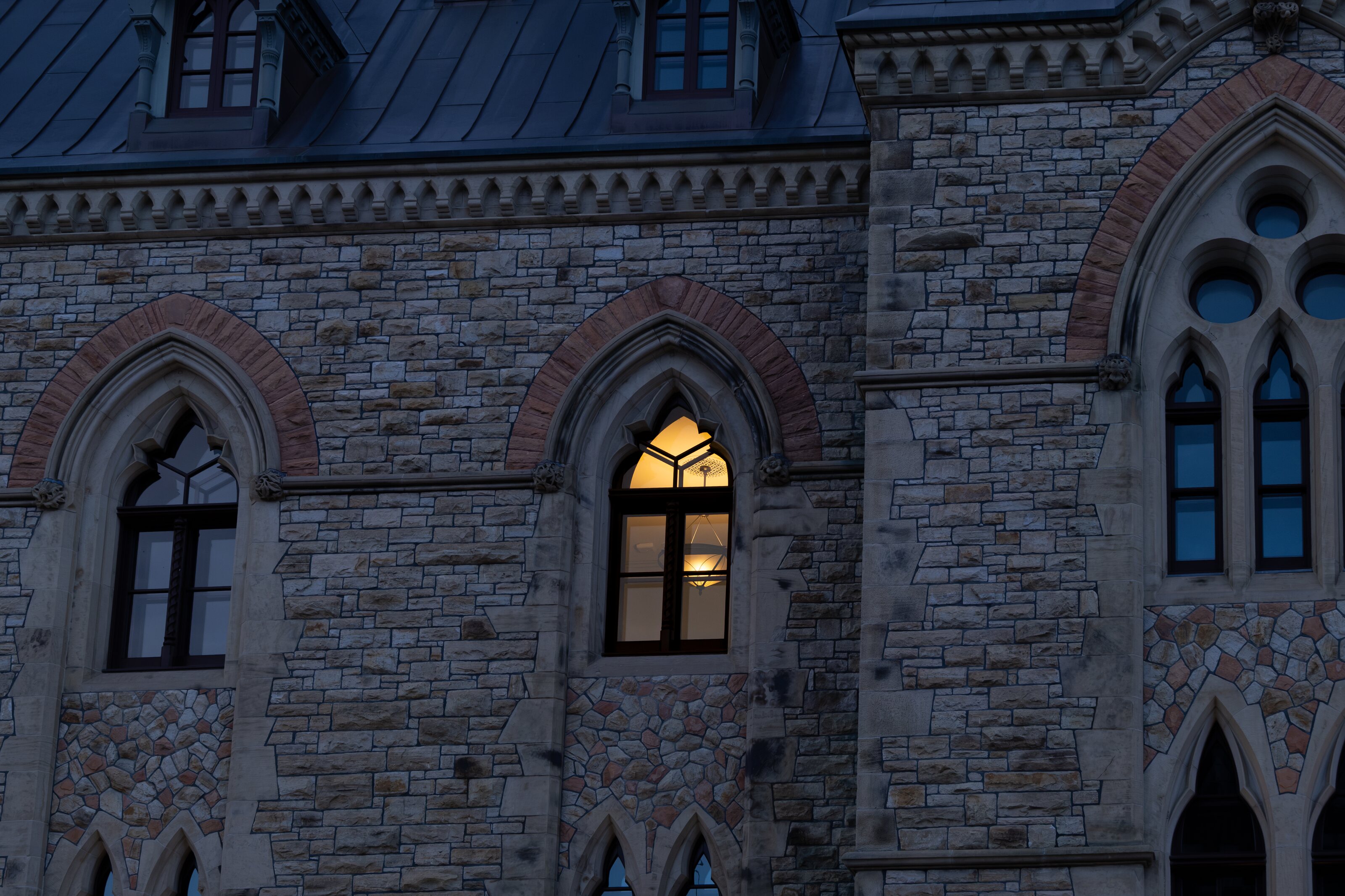 A single lit Gothic window in Parliament’s stone facade