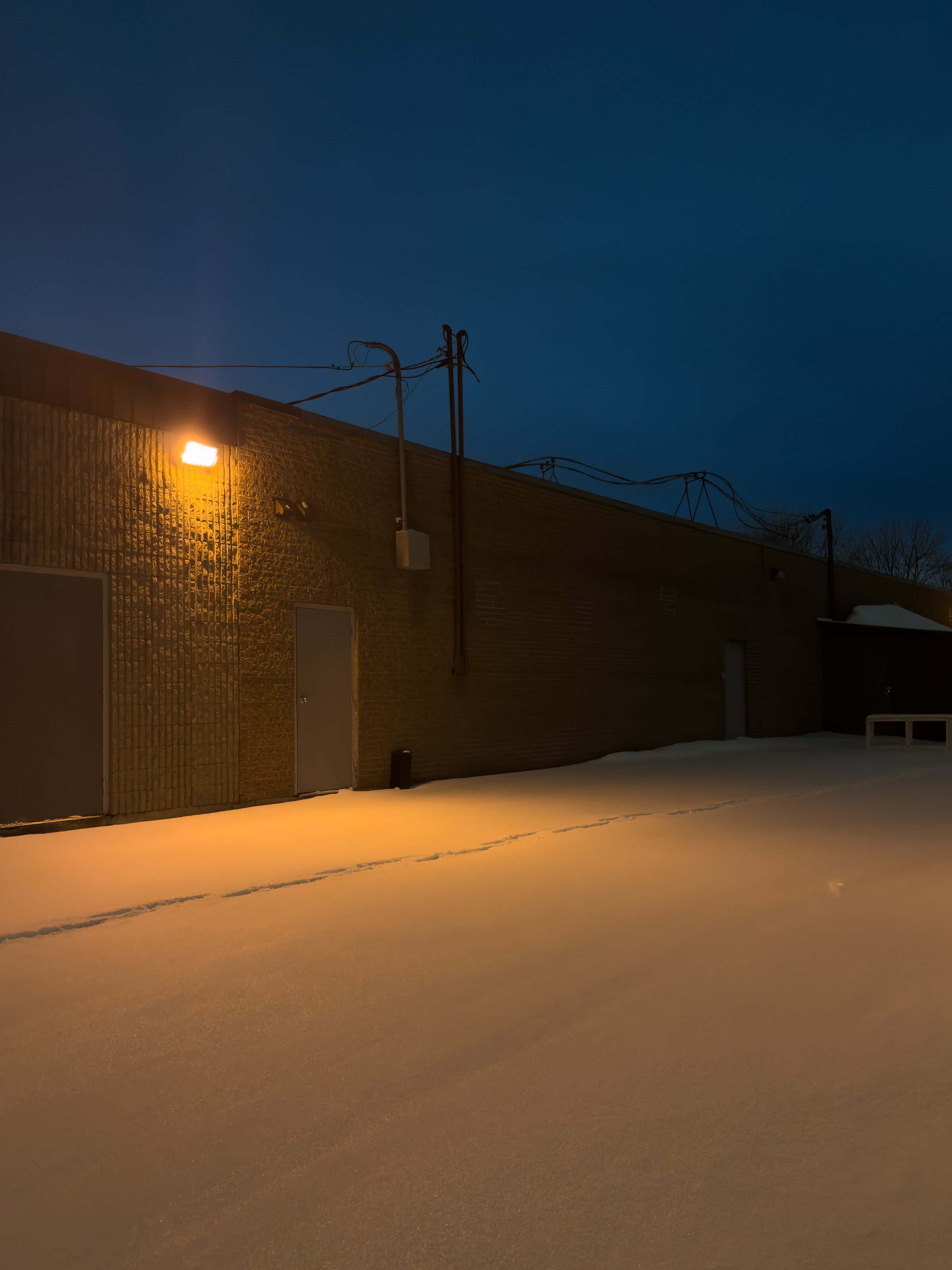 Snow-covered ground beneath an amber light at blue hour