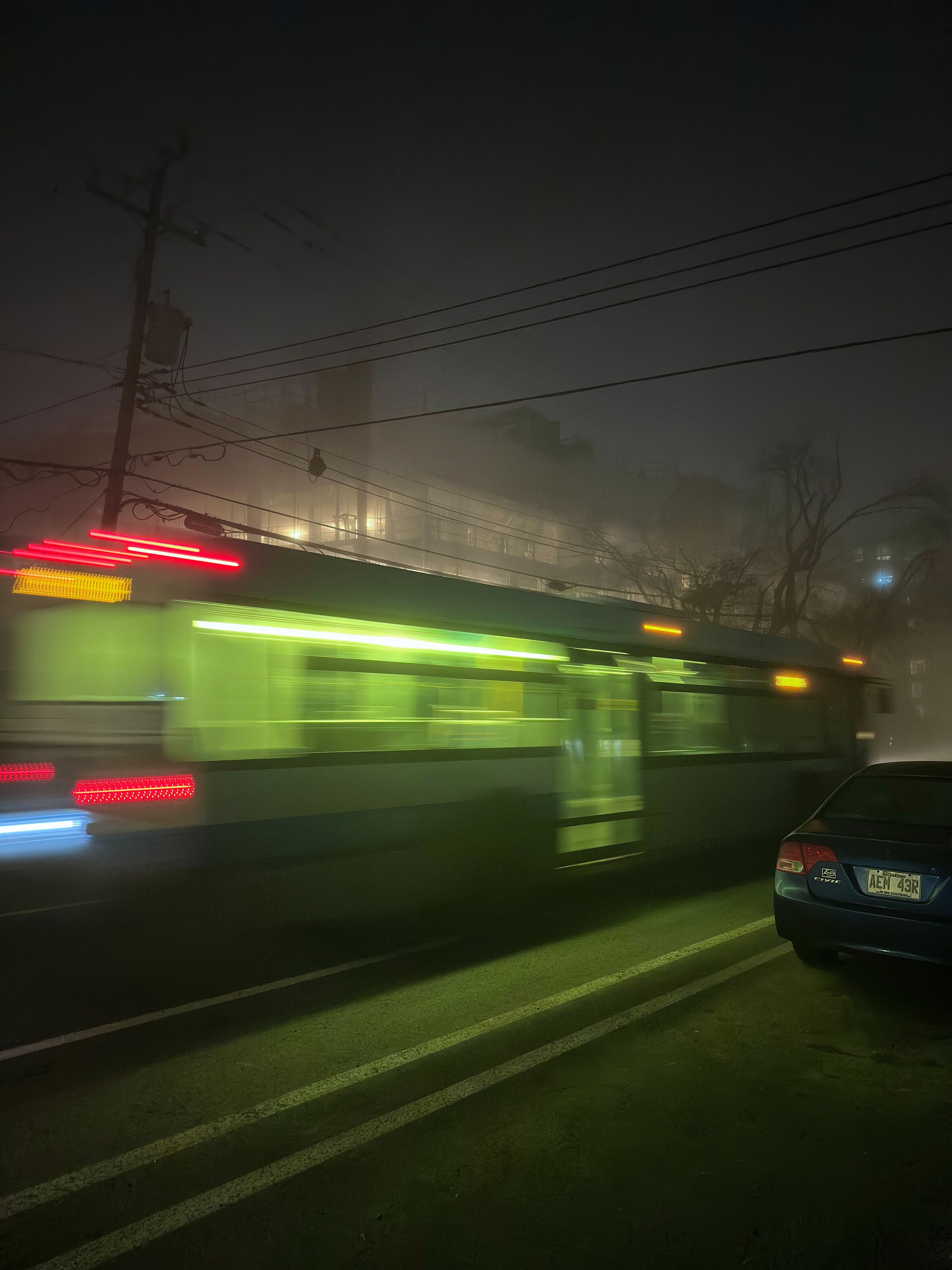 A city bus passing through rain at night
