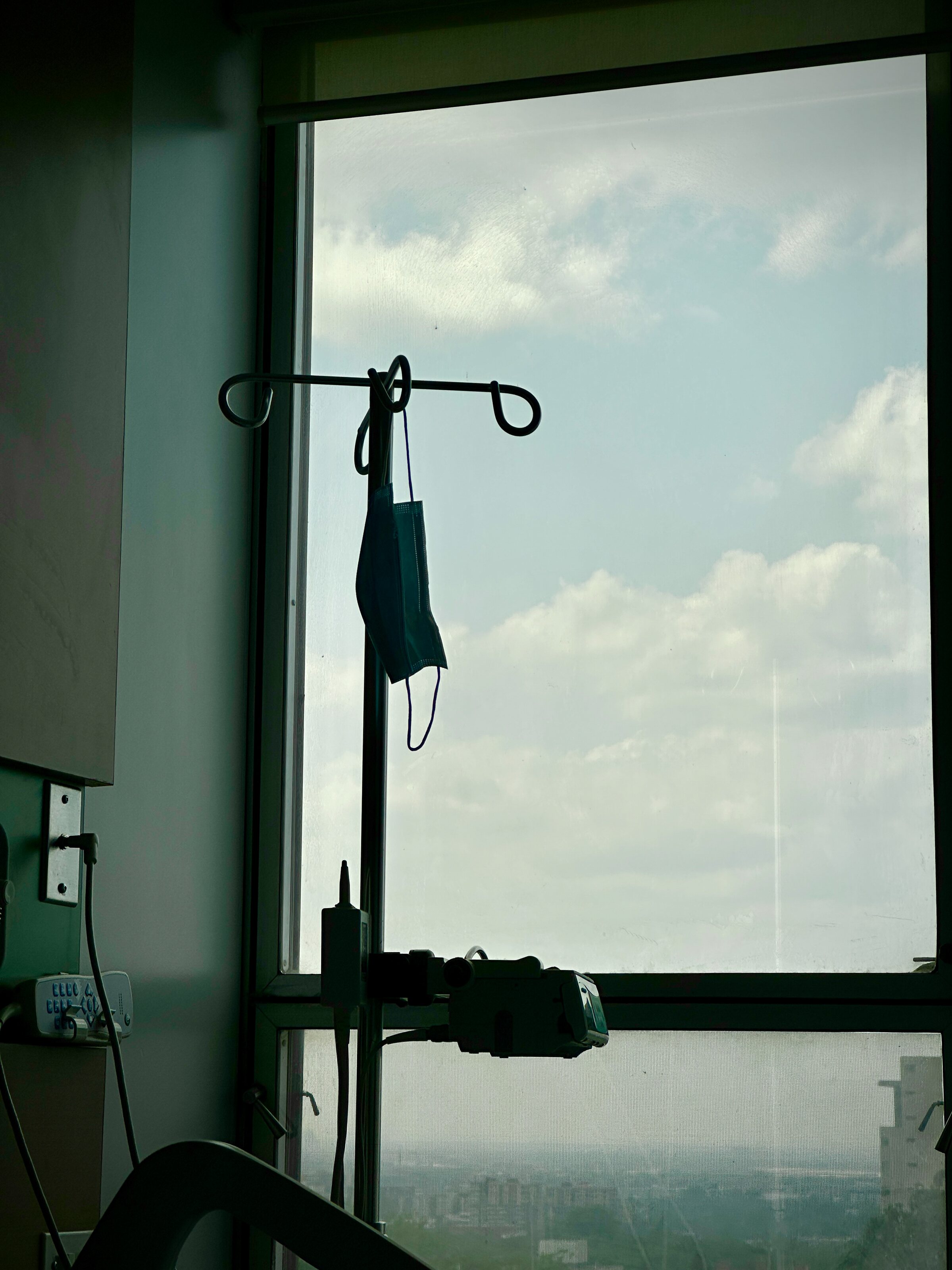 An IV pole silhouetted against a hospital window